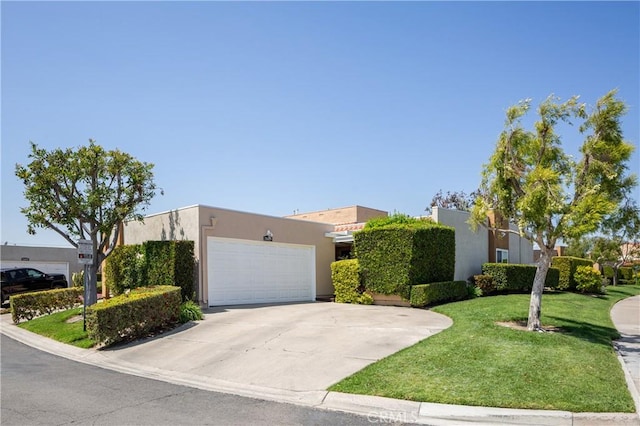 view of front of property featuring stucco siding, a front lawn, driveway, and a garage