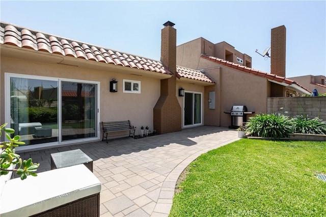 back of house featuring a patio, stucco siding, and a tiled roof