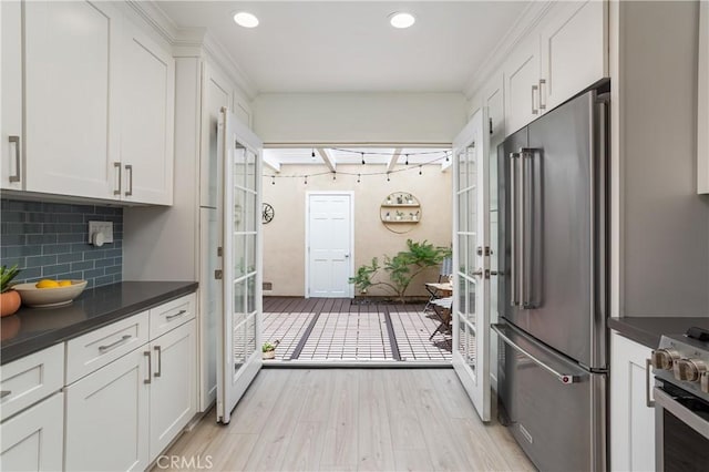 kitchen with appliances with stainless steel finishes, french doors, dark countertops, light wood-style floors, and recessed lighting