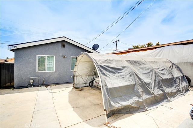 view of property exterior with a patio area, stucco siding, and fence