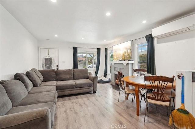 living room with a wall mounted AC, recessed lighting, and light wood finished floors