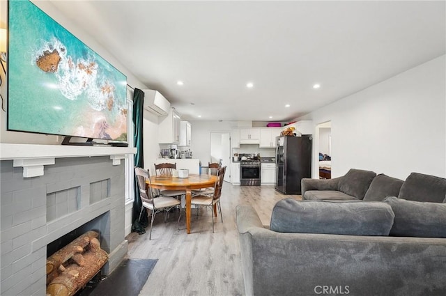 living area featuring light wood-style floors, a fireplace, a wall mounted AC, and recessed lighting