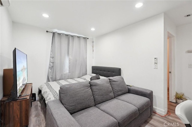 bedroom featuring wood finished floors, recessed lighting, an AC wall unit, and baseboards