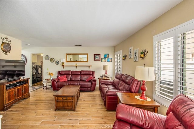 living room featuring independent washer and dryer and light wood-style floors