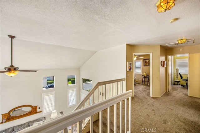 hallway featuring carpet floors, a textured ceiling, and baseboards