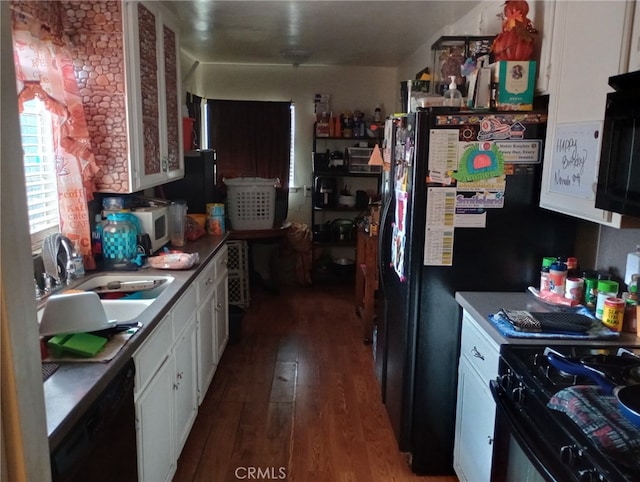 kitchen with dark wood-style floors, black appliances, white cabinets, and a sink