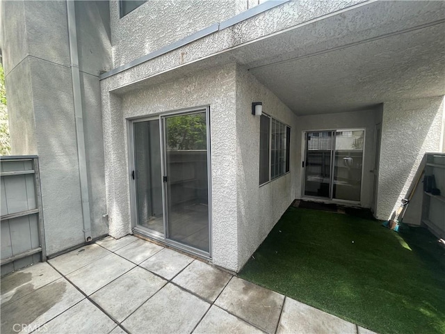 property entrance featuring stucco siding and a patio
