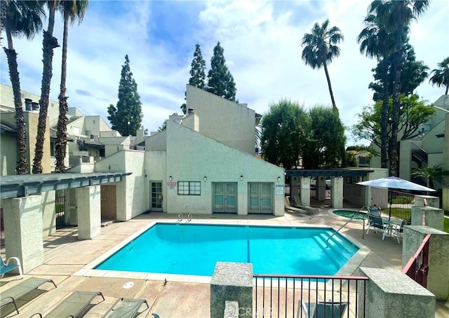 community pool with a patio and fence