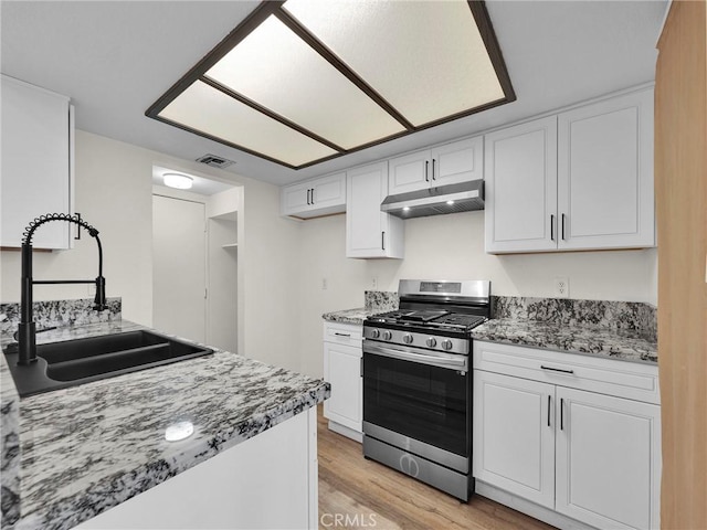 20155 Keswick St Unit 117, Winnetka, CA 91306 - kitchen featuring stainless steel gas stove, under cabinet range hood, a sink, light wood finished floors, and white cabinets