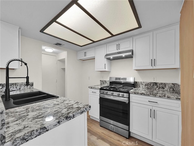 20155 Keswick St Unit 117, Winnetka, CA 91306 - kitchen featuring stainless steel range with gas cooktop, under cabinet range hood, white cabinets, light wood-style floors, and light stone counters