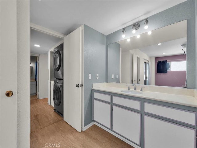 20155 Keswick St Unit 117, Winnetka, CA 91306 - bathroom featuring stacked washer / drying machine, wood finished floors, vanity, baseboards, and recessed lighting
