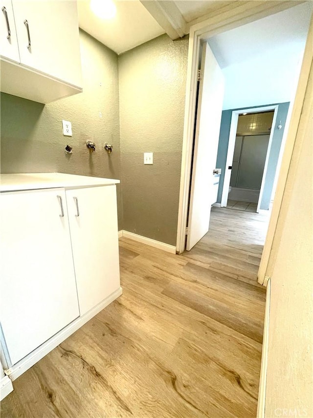 20155 Keswick St Unit 117, Winnetka, CA 91306 - laundry room featuring light wood-type flooring, cabinet space, and a textured wall