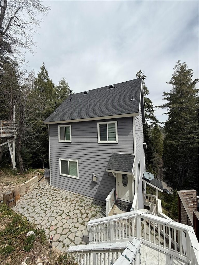back of property featuring roof with shingles and a patio