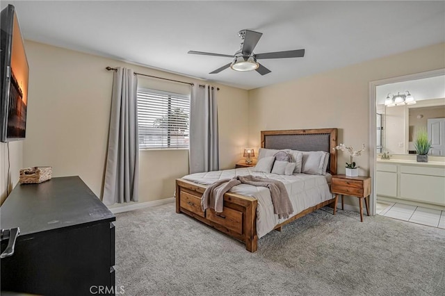 bedroom featuring ensuite bath, ceiling fan, baseboards, and light carpet