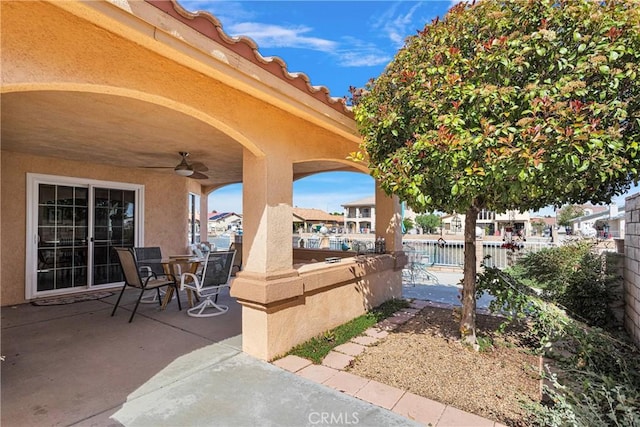 view of patio featuring a ceiling fan, outdoor dining area, and fence