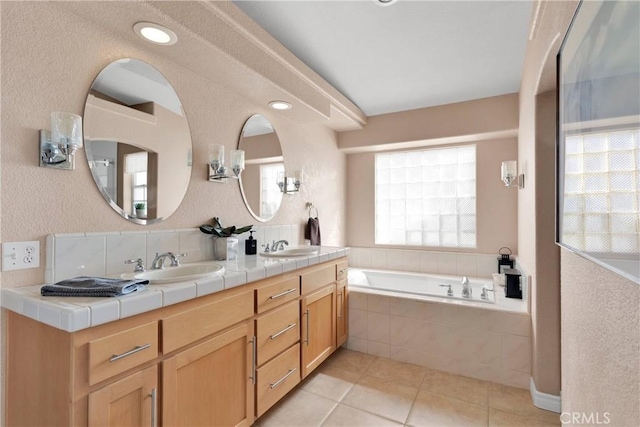 full bathroom featuring tile patterned flooring, a bath, double vanity, and a textured wall