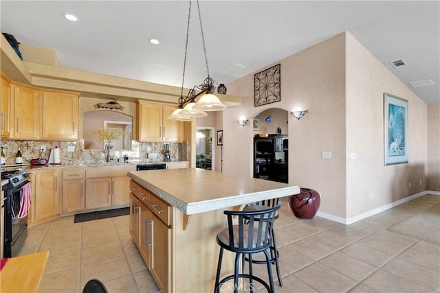 kitchen featuring arched walkways, black gas stove, light brown cabinetry, light countertops, and recessed lighting