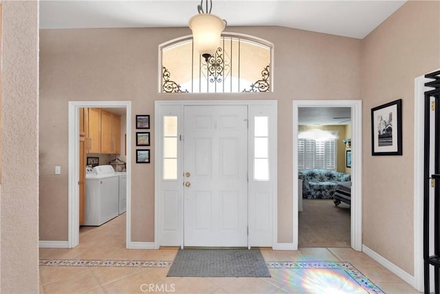 entrance foyer with separate washer and dryer, light tile patterned floors, baseboards, and high vaulted ceiling
