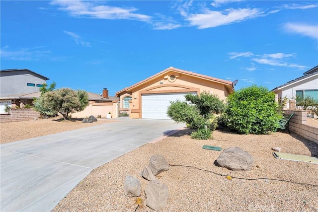 view of front of house with concrete driveway, stucco siding, an attached garage, and fence