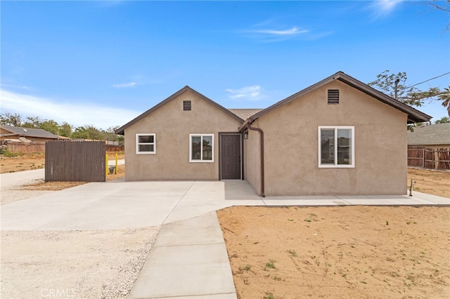 view of front of house featuring fence, stucco siding, and a patio