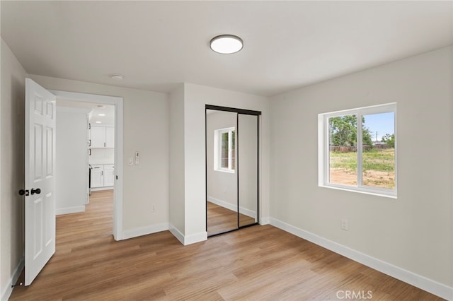 unfurnished bedroom with baseboards, light wood-type flooring, and a closet