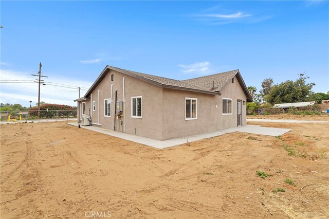 view of property exterior with stucco siding and fence