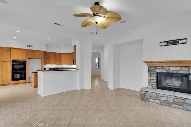 34113 Castle Pines Dr, Yucaipa, CA 92399 - kitchen with arched walkways, open floor plan, a ceiling fan, light tile patterned floors, and a fireplace
