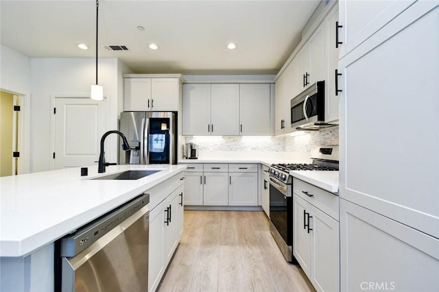 1053 Tiburon Way, San Luis Obispo, CA 93401 - kitchen featuring appliances with stainless steel finishes, a sink, light countertops, decorative backsplash, and light wood-style floors