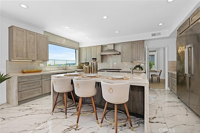 28 Brownsbury Rd, Laguna Niguel, CA 92677 - kitchen with high end fridge, wall chimney range hood, decorative backsplash, recessed lighting, and a center island with sink