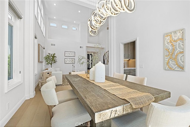 28 Brownsbury Rd, Laguna Niguel, CA 92677 - dining space featuring a chandelier, light wood-type flooring, a towering ceiling, baseboards, and recessed lighting