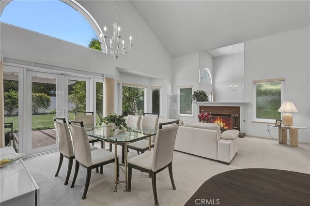 2146 Via Aguila, San Clemente, CA 92673 - dining area featuring high vaulted ceiling, light colored carpet, french doors, a chandelier, and a warm lit fireplace