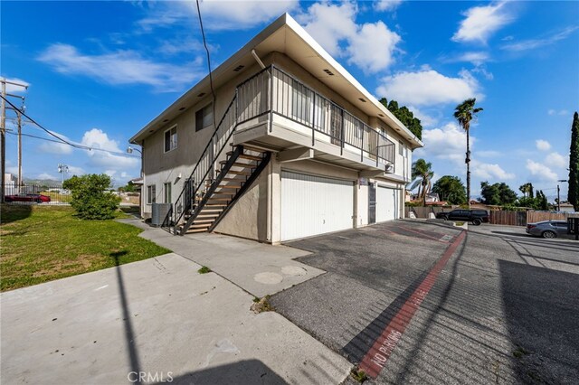 2004 Palm Ave, Highland, CA 92346 - view of property exterior featuring an attached garage, stucco siding, a balcony, stairway, and asphalt driveway