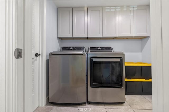 laundry room featuring washing machine and clothes dryer, cabinet space, and light tile patterned floors