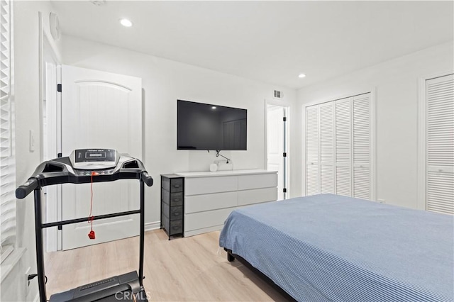 bedroom with light wood finished floors, recessed lighting, and two closets