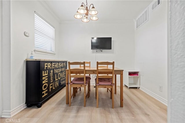 dining space featuring light wood-type flooring, a chandelier, crown molding, and baseboards