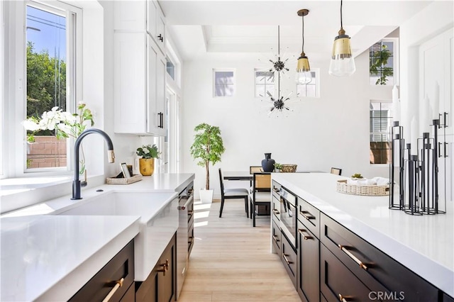 17 Candlewood, Irvine, CA 92620 - kitchen featuring light countertops, decorative light fixtures, a sink, and light wood-style flooring