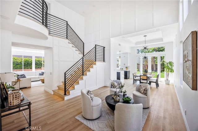 17 Candlewood, Irvine, CA 92620 - living area with a towering ceiling, stairway, light wood-style floors, a tray ceiling, and baseboards
