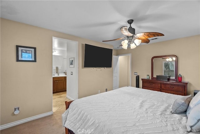 bedroom with light colored carpet, ensuite bath, baseboards, and a ceiling fan