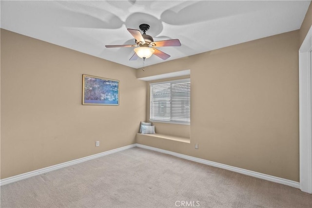 carpeted spare room featuring a ceiling fan and baseboards