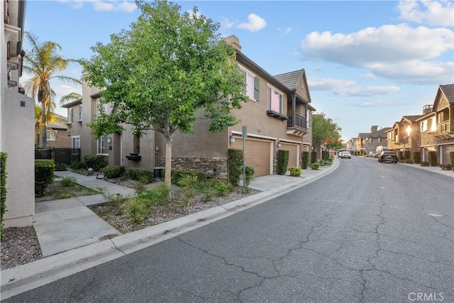 view of asphalt road featuring a residential view and curbs