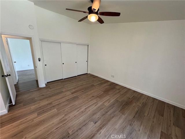 unfurnished bedroom featuring wood finished floors, baseboards, a closet, and ceiling fan