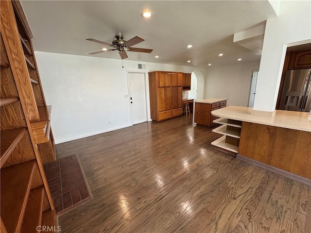 unfurnished living room with a ceiling fan, arched walkways, recessed lighting, dark wood-style flooring, and baseboards