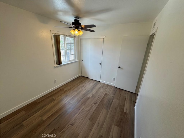 unfurnished bedroom with wood finished floors, a closet, baseboards, and ceiling fan