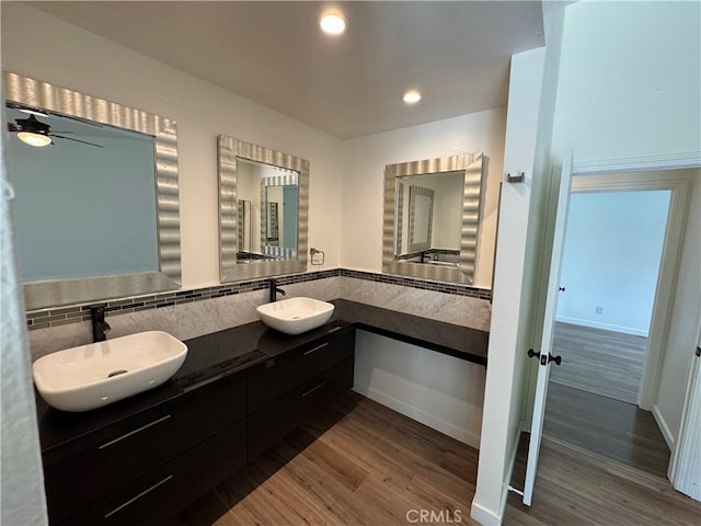 bathroom with wood finished floors, double vanity, baseboards, ceiling fan, and recessed lighting