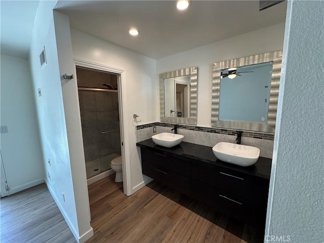 bathroom with wood finished floors, a shower stall, double vanity, toilet, and recessed lighting
