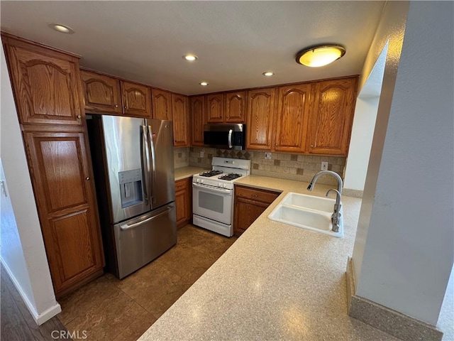 kitchen with stainless steel appliances, a sink, tasteful backsplash, light countertops, and brown cabinetry