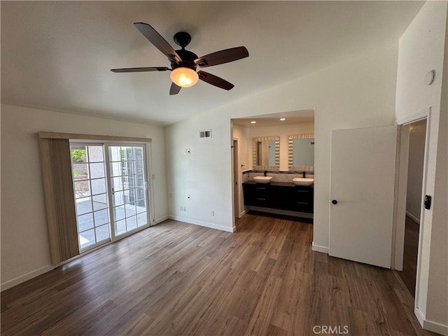 unfurnished bedroom featuring access to outside, lofted ceiling, wood finished floors, baseboards, and ensuite bath