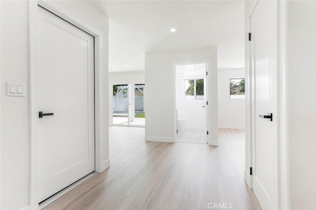hall with light wood-style floors, recessed lighting, and baseboards