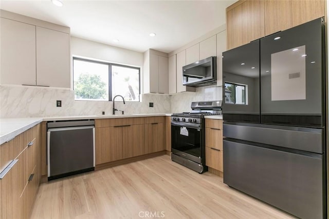 kitchen featuring stainless steel appliances, modern cabinets, a sink, and recessed lighting