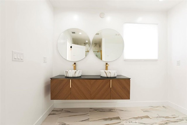 hall with light marble finish flooring, baseboards, and a sink